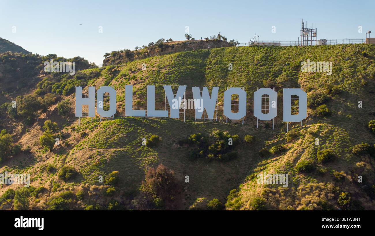 Vue aérienne de l'emblématique panneau Hollywood situé sur les pentes escarpées du mont Lee, entouré d'une végétation sèche et d'un ciel bleu clair à Los Angeles, Banque D'Images