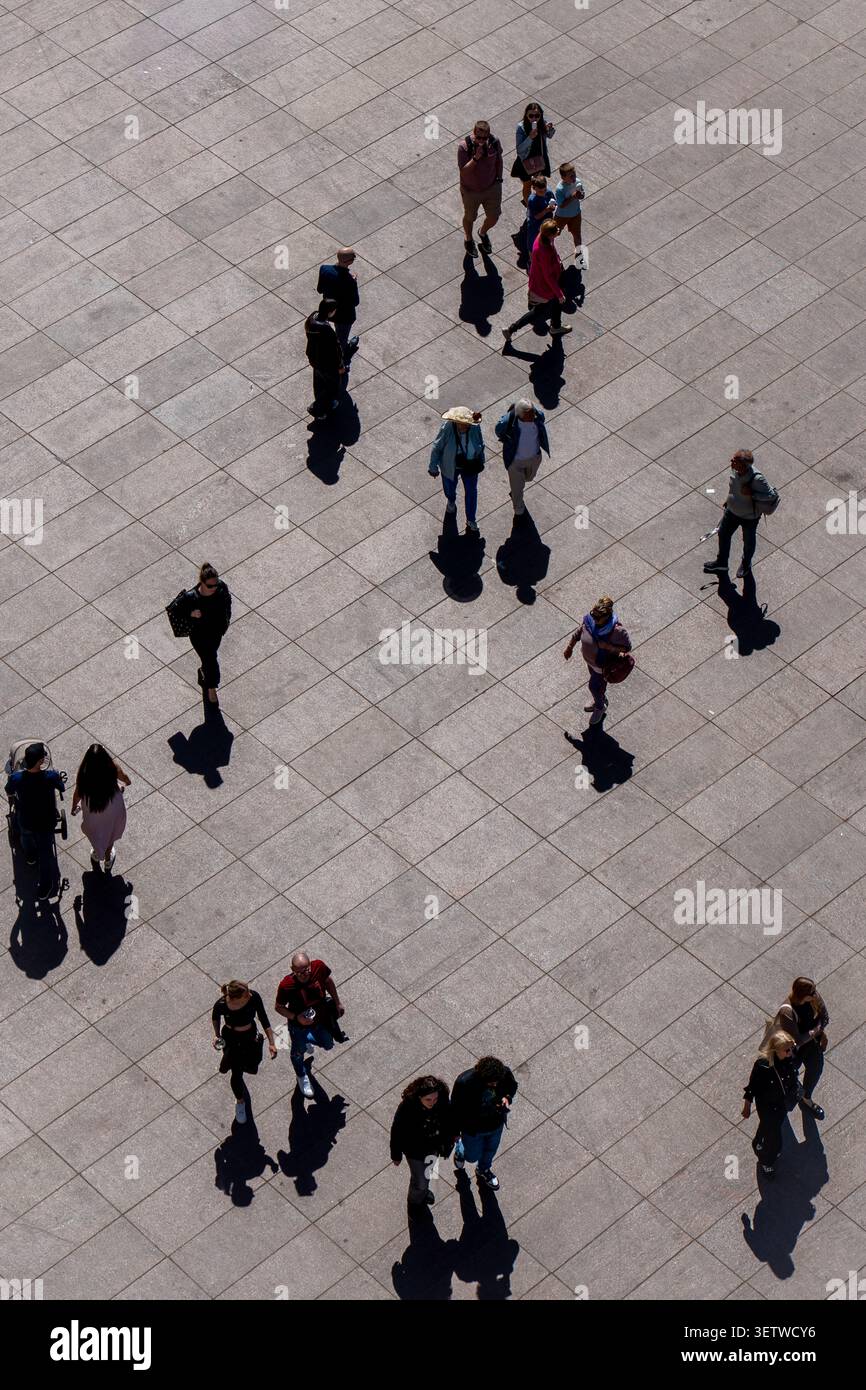Vue en grand angle des piétons projetant de longues ombres sur la place urbaine ensoleillée de Varsovie Banque D'Images