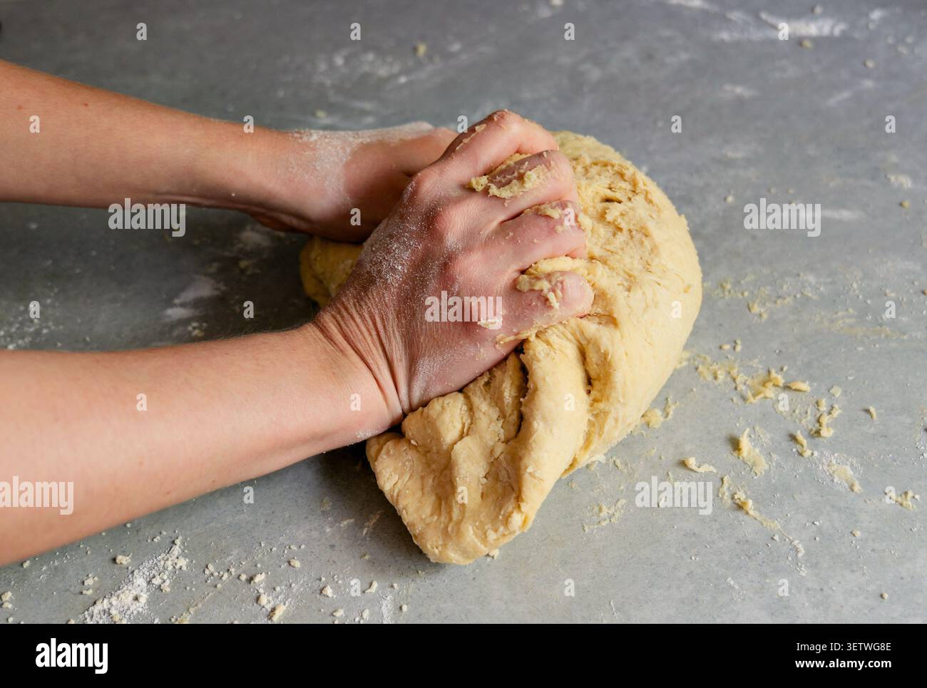 Mains de boulanger façonnant une boule de pâte à pâte brisée. Gros plan des mains d'une personne pétrissant et formant une boule solide de pâte crue maison sur un gris Banque D'Images