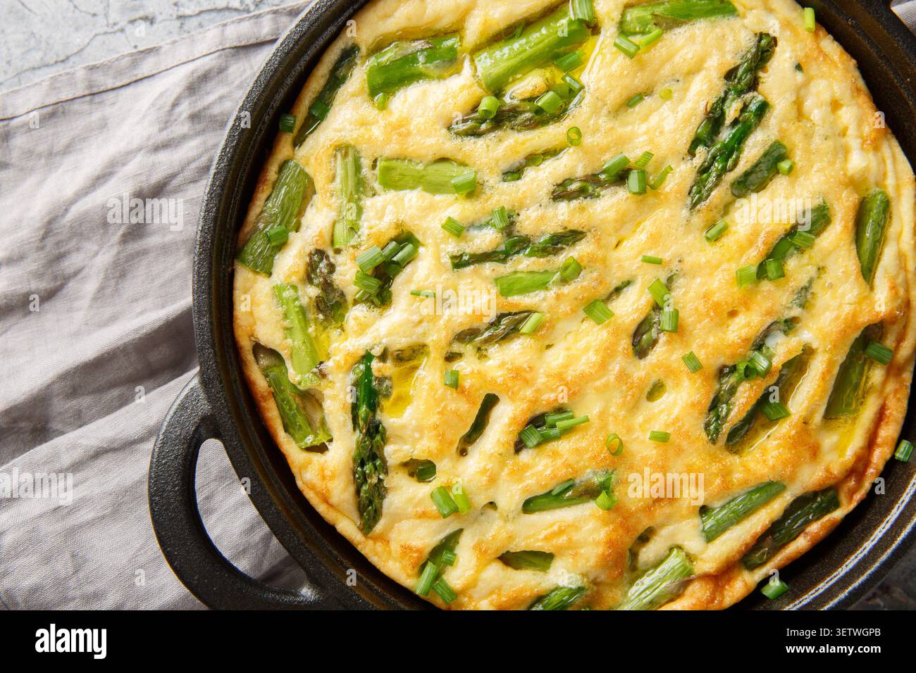 Frittata de légumes cuits au four maison avec des asperges vertes en gros plan dans la poêle sur la table. Vue horizontale de dessus Banque D'Images