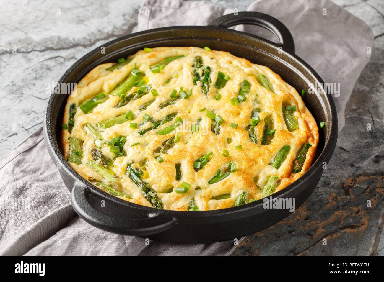 Frittata de légumes cuits au four maison avec des asperges vertes en gros plan dans la poêle sur la table. Horizontal Banque D'Images