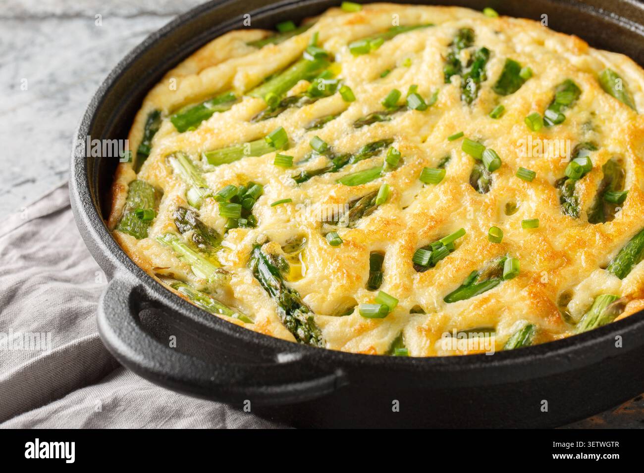 Délicieuse frittata d'asperges vertes aux herbes fraîches en gros plan dans la poêle sur la table. Horizontal Banque D'Images