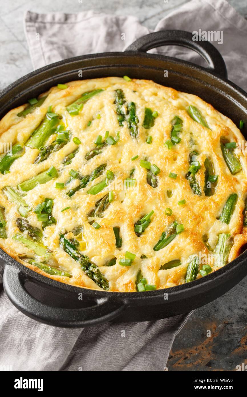 Frittata savoureux cuit au four avec des asperges et une herbe fraîche en gros plan dans la poêle sur la table. Vertical Banque D'Images