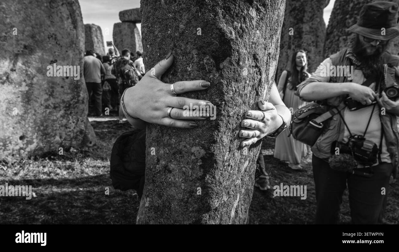 Image en noir et blanc d'un fidèle embrassant une pierre sacrée après le solstice d'été à Stonehenge. Banque D'Images