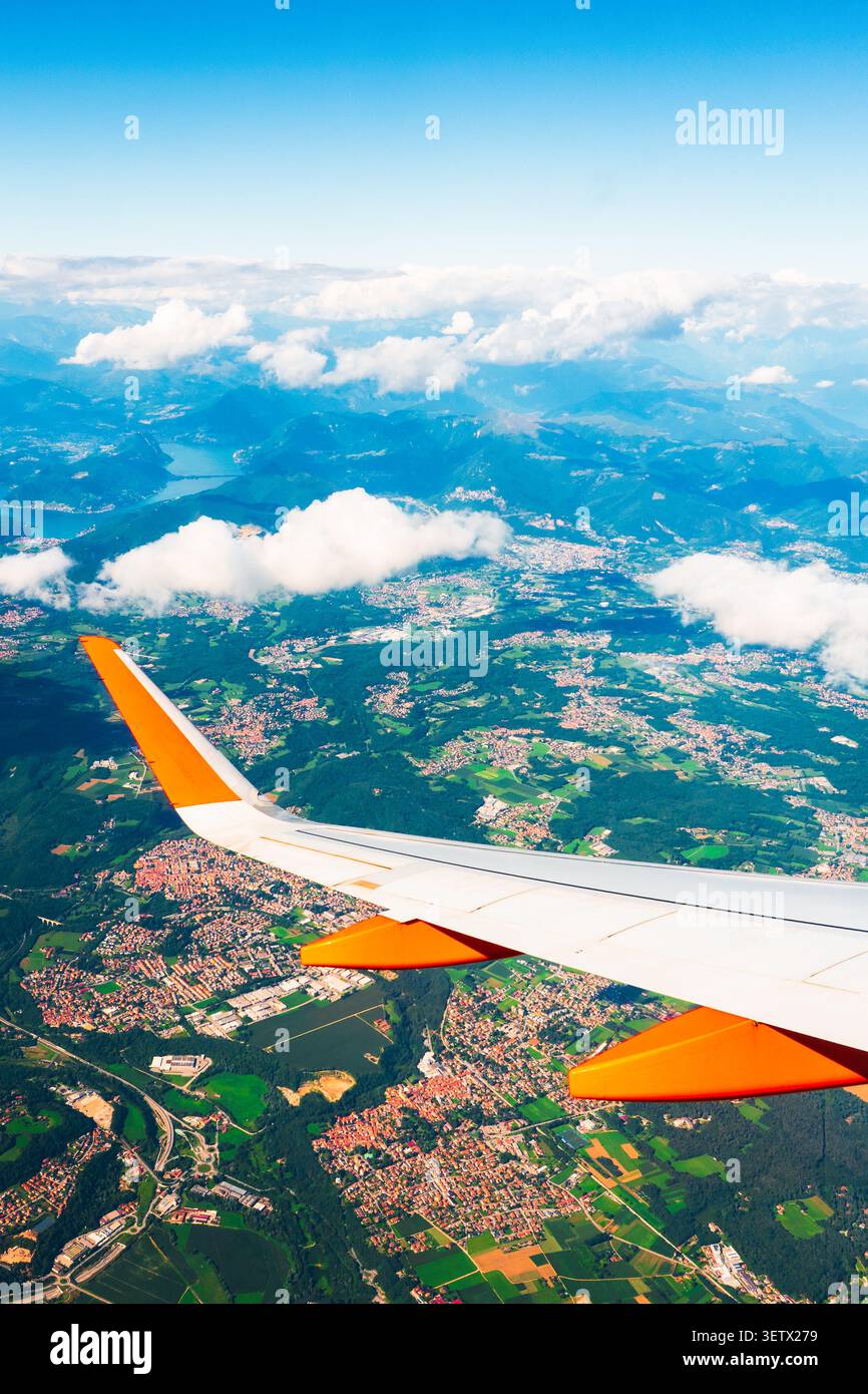 Point de vue du siège passager d'un avion commercial aérien au décollage. Aile d'avion au-dessus des terres agricoles des villes et des montagnes vues à travers la victoire de l'avion Banque D'Images