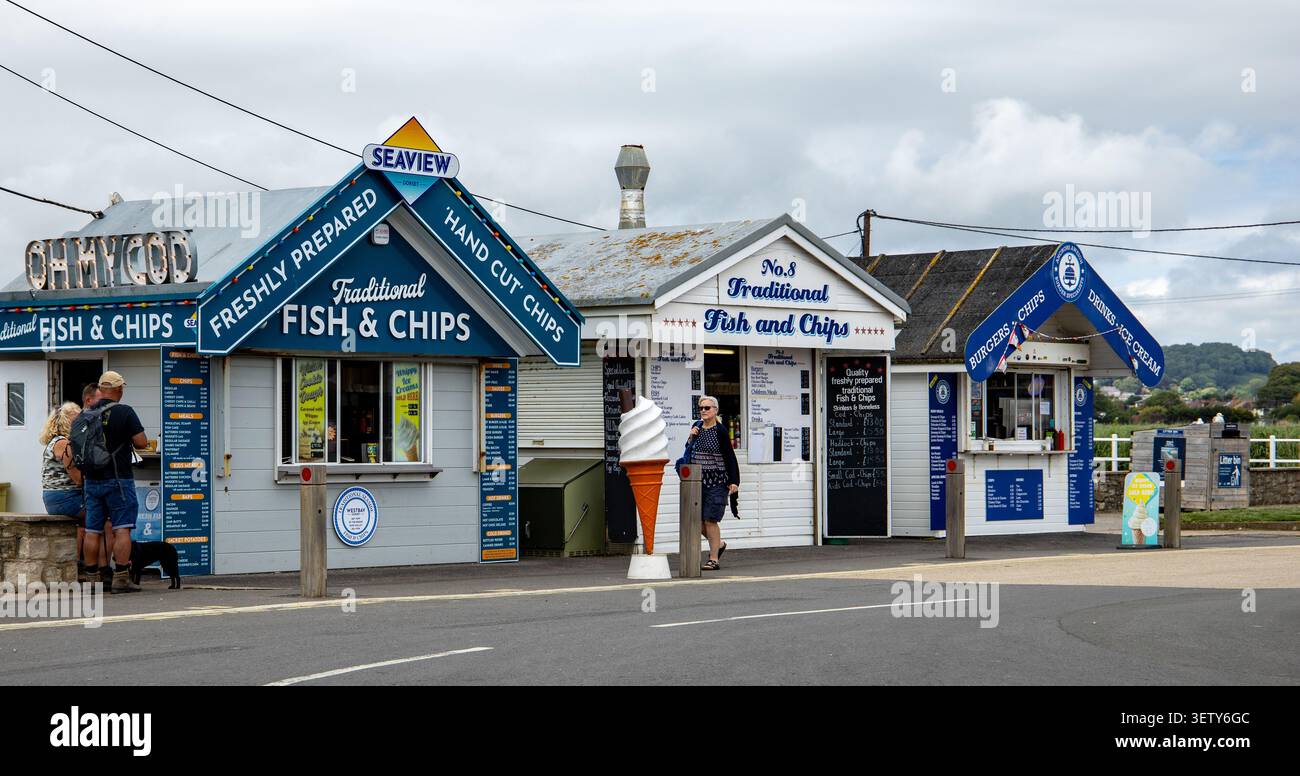 Petits kiosques en bois colorés en bord de mer vendant du poisson et des frites à emporter et de la crème glacée à un endroit côtier West Bat Dorset Banque D'Images