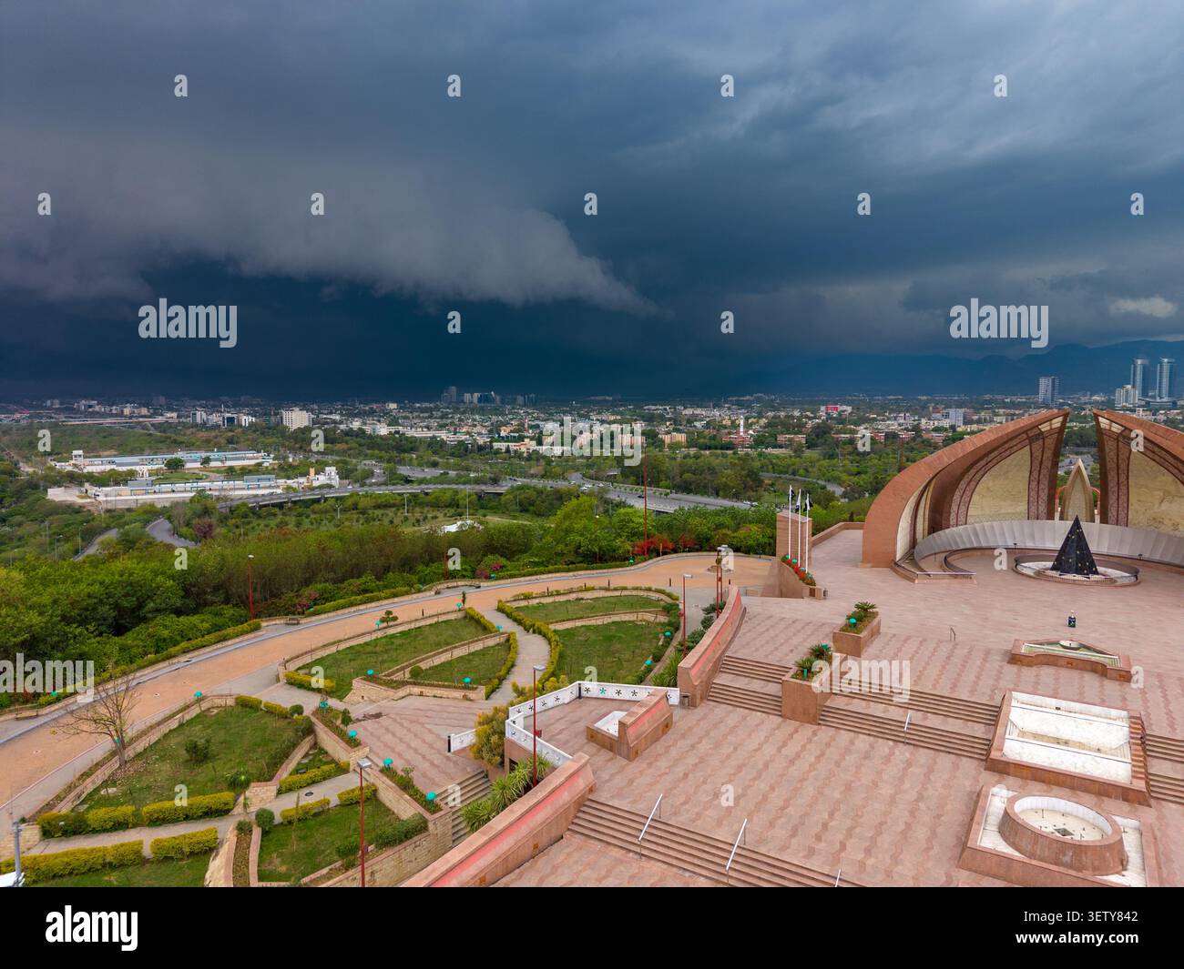 Vue aérienne du monument du Pakistan avec sa structure en forme de pétales, entouré de jardins et de terrasses sous un ciel orageux spectaculaire à Islamabad, Isl Banque D'Images