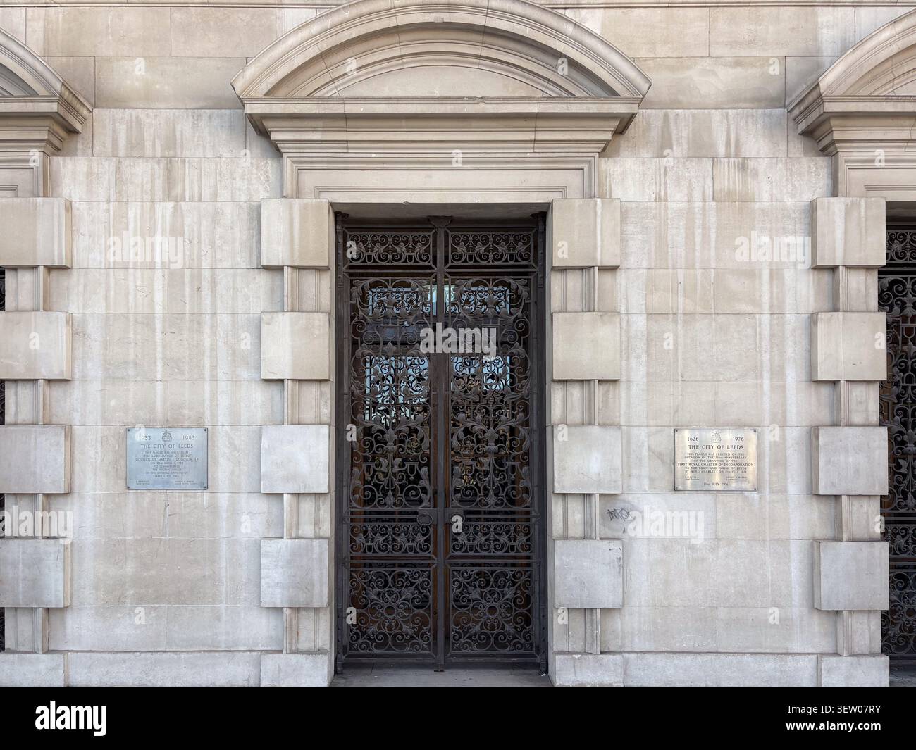 Entrée en calcaire néo-classique du Leeds Civic Hall, West Yorkshire, Angleterre avec des portes complexes en fer forgé et des plaques murales commémoratives. Banque D'Images