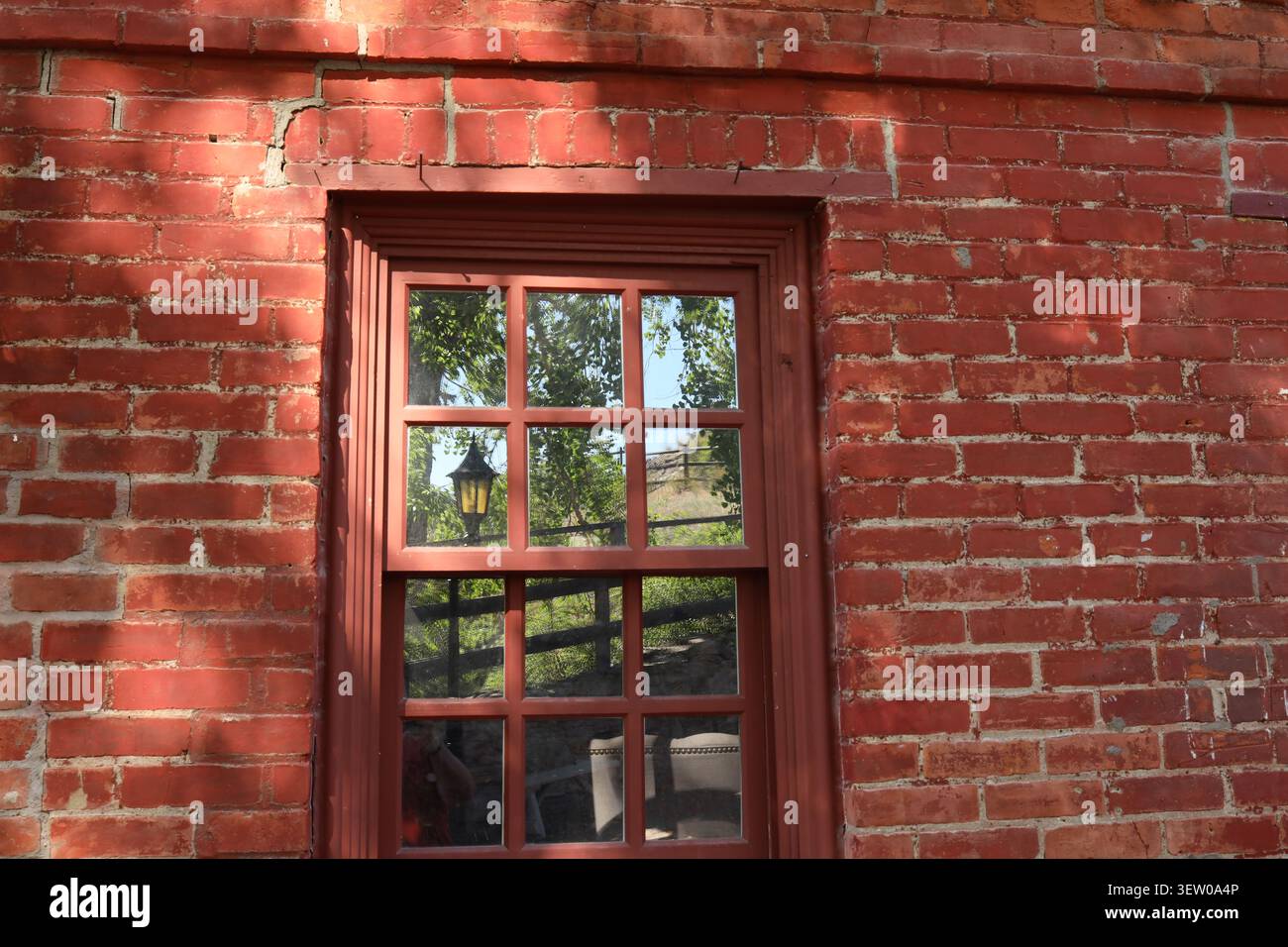 Fenêtre de bâtiment historique en briques reflétant des arbres et un lampadaire vintage à Reeder's Alley, Helena, Montana, États-Unis. Banque D'Images