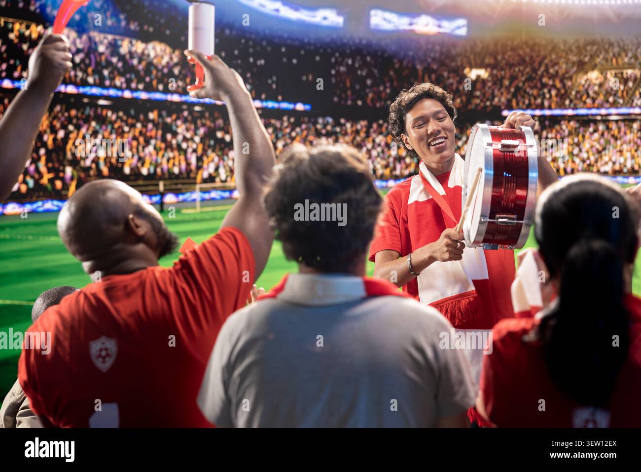 Homme enthousiaste sur le stade de football battant le tambour, encourageant les joueurs. Leader des fans de football galvanisant une grande foule dans l'arène sportive en direct pendant le jour du match Banque D'Images