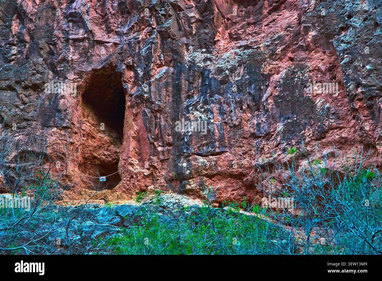Red Rock Cliff face avec Cave Entrance et Desert Vegetation dans le sud-ouest éloigné Banque D'Images
