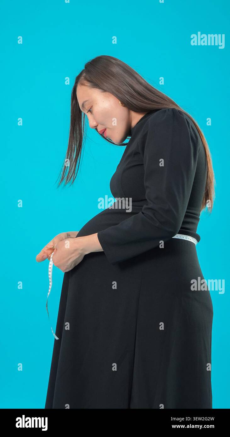 Femme enceinte regardant son ventre avec un toucher doux et attentionné maintenant Banque D'Images
