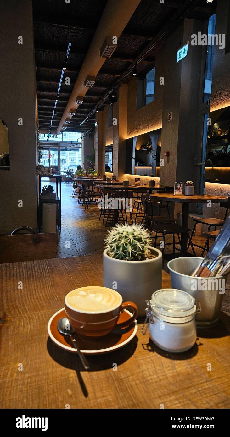 Café cappuccino servi dans un café moderne décoré d'un intérieur chaleureux - Image de stock capturée avec un smartphone