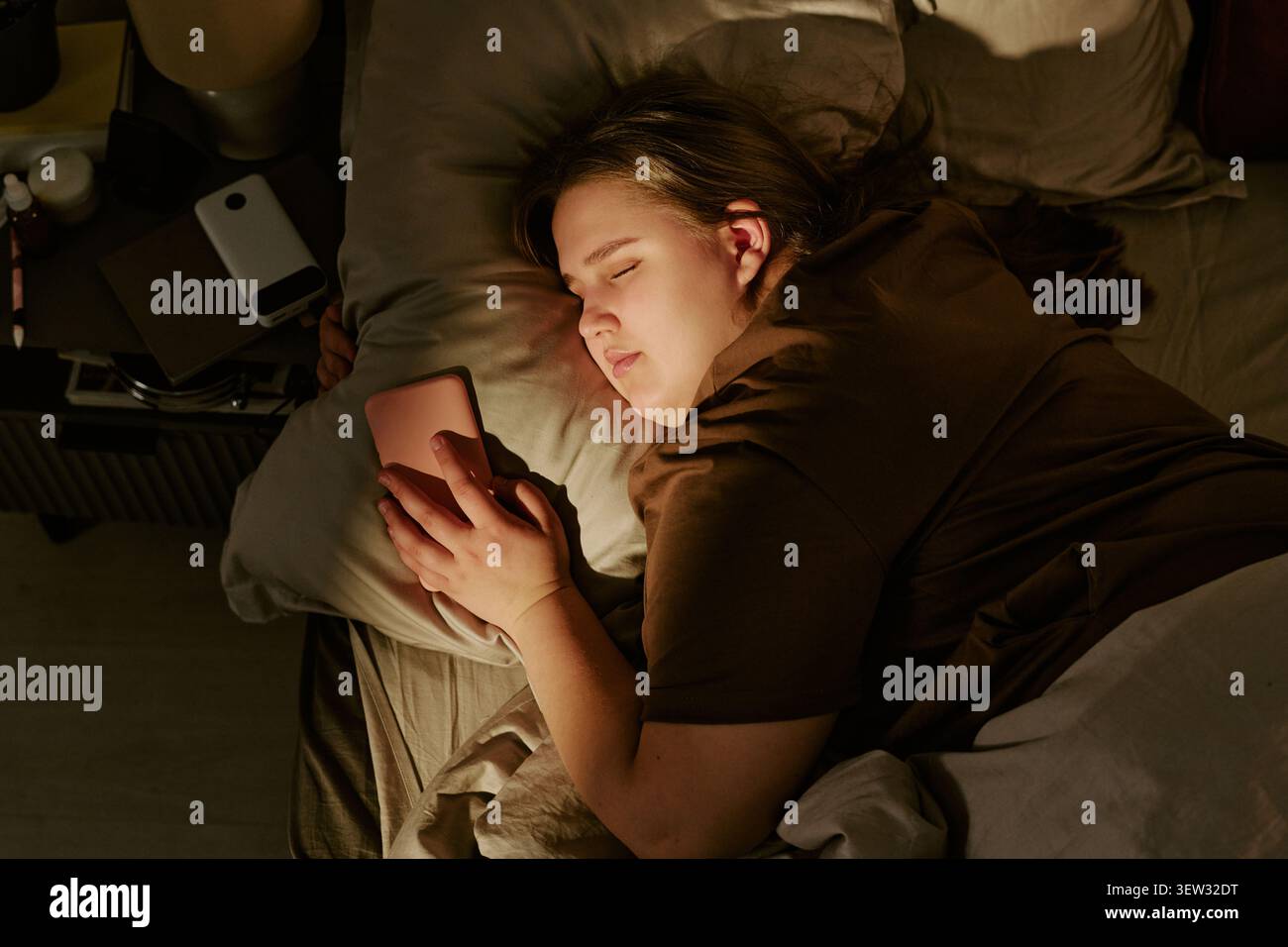 Femme de taille plus dormant avec smartphone dans le lit pour Digital Detox Banque D'Images