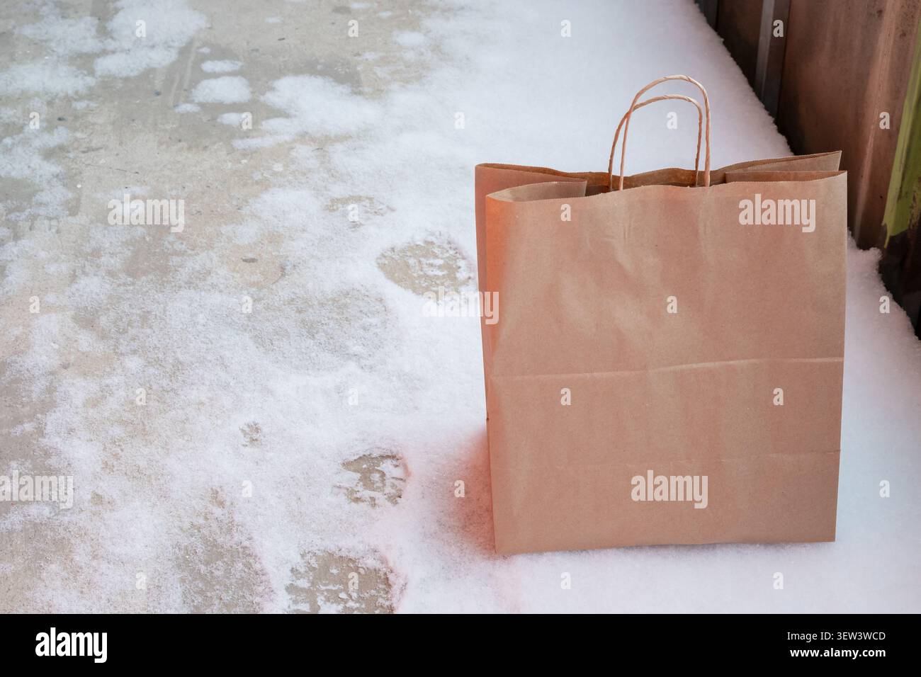 Sac de livraison en papier brun sur plancher de balcon recouvert de neige. service de livraison de nourriture, emballage écologique, shopping Banque D'Images