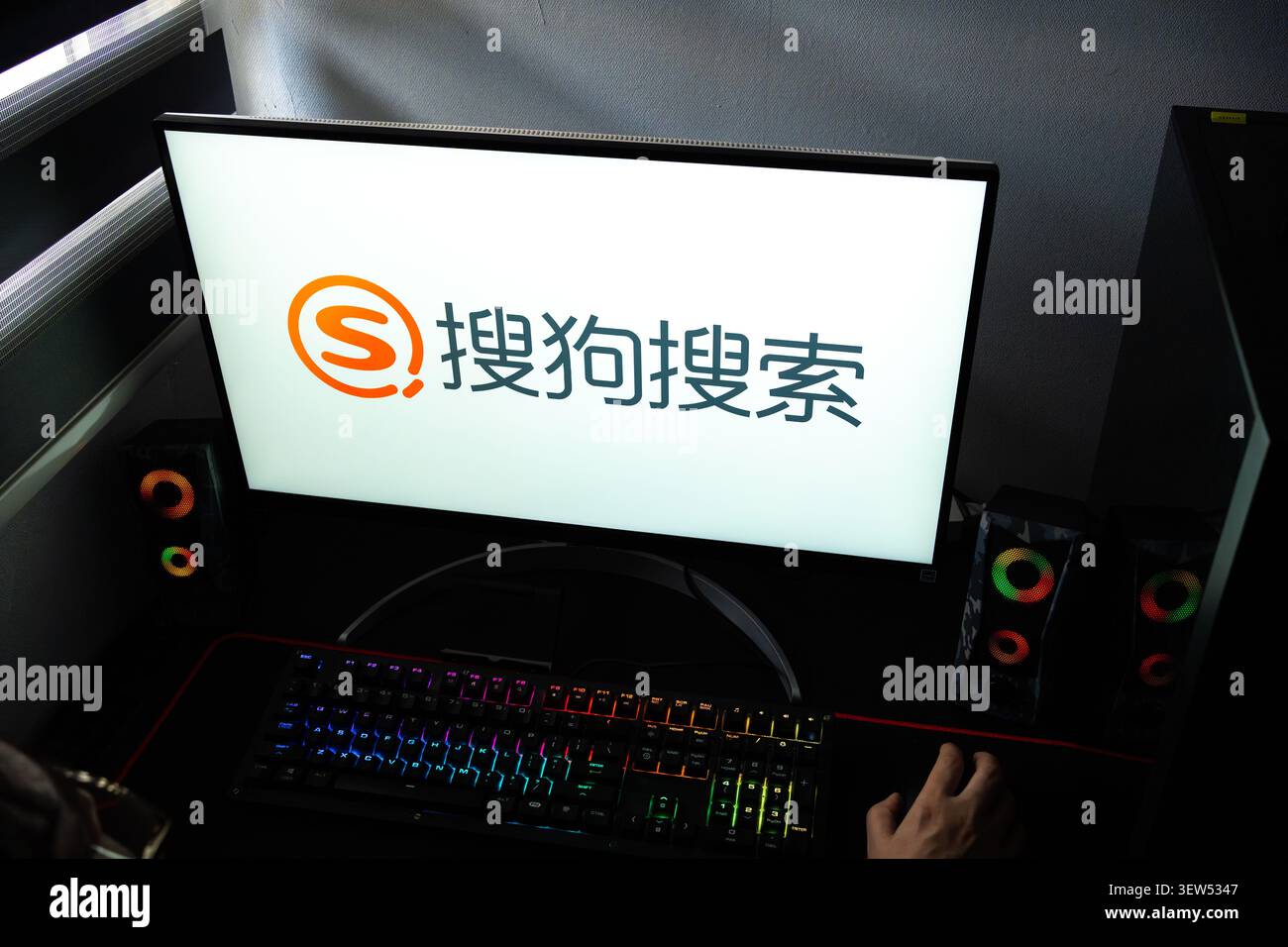 Une personne à un bureau avec le logo de la recherche chinoise Sogou (搜狗) affiché sur un ordinateur Banque D'Images
