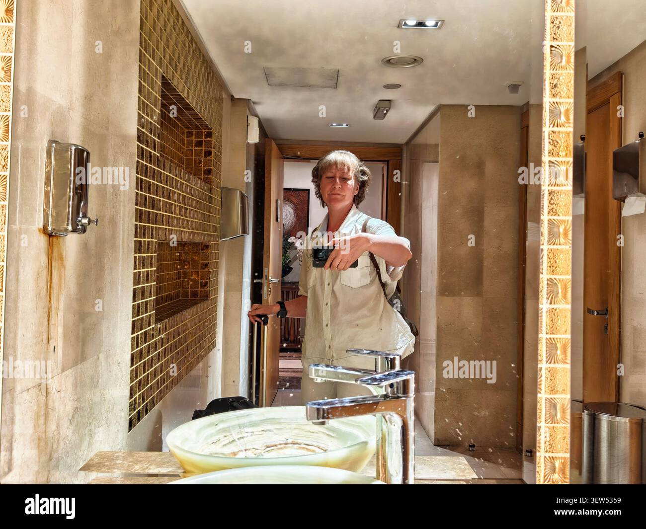 Femme profitant d'un moment dans une salle de bain, prenant un selfie avec un smartphone tout en étant habillée de façon décontractée et à l'air détendu Banque D'Images