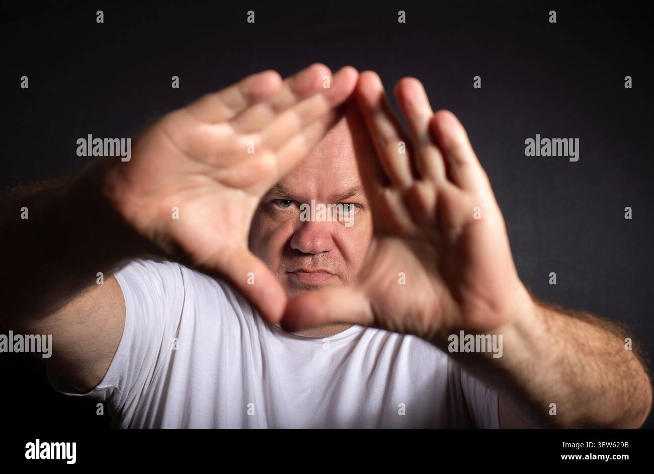 Homme cadrant la scène avec les mains tout en regardant la caméra Banque D'Images