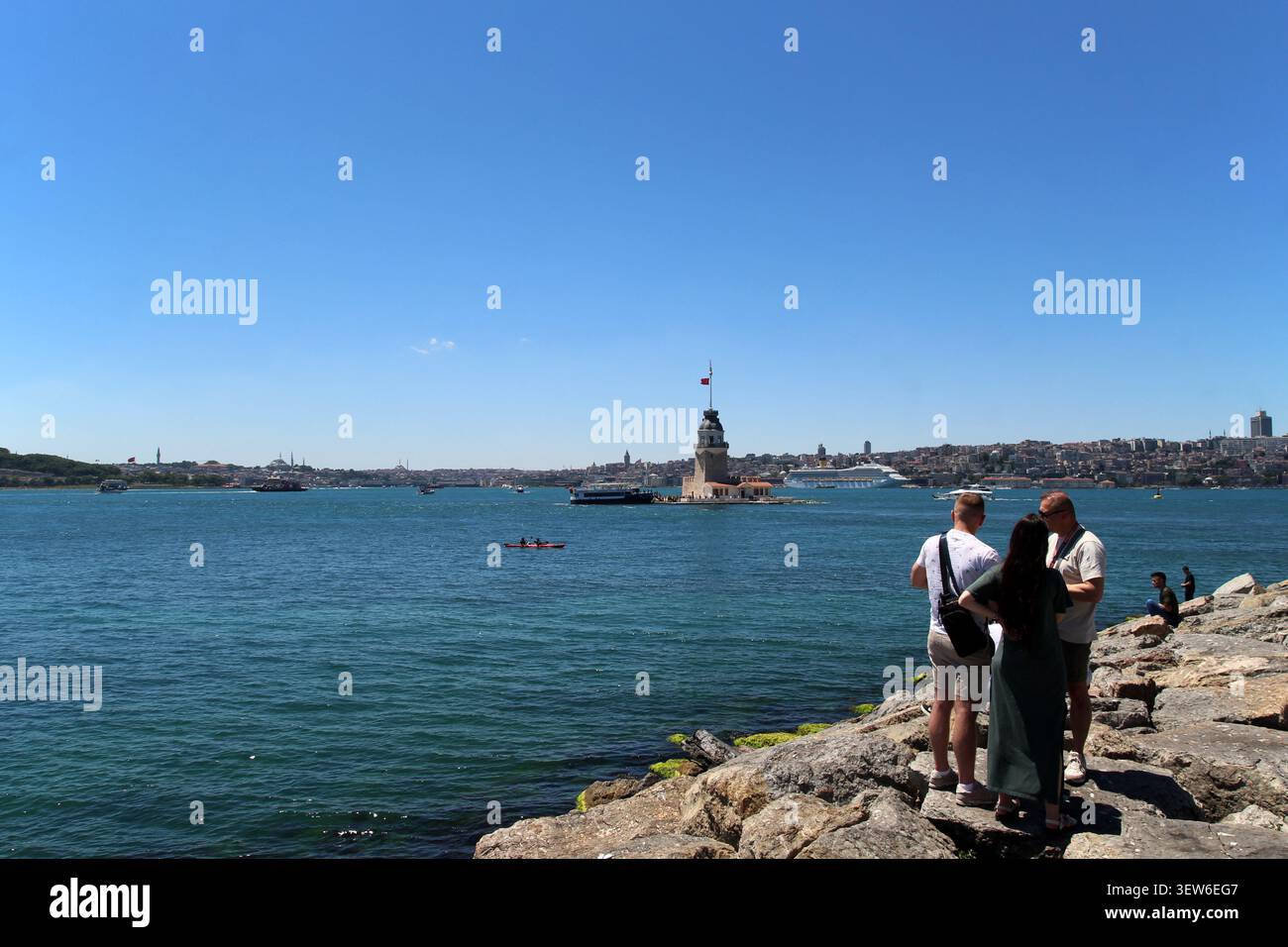 Touristes regardant la Tour de Maiden de la côte d'Uskudar, Istanbul, Turquie, journée ensoleillée vue panoramique sur le Bosphore avec des bateaux et un ciel bleu clair Banque D'Images