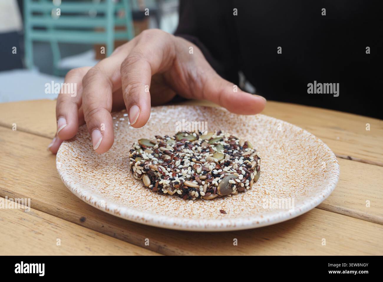 Main atteint pour une collation de graines rondes sur une assiette Banque D'Images