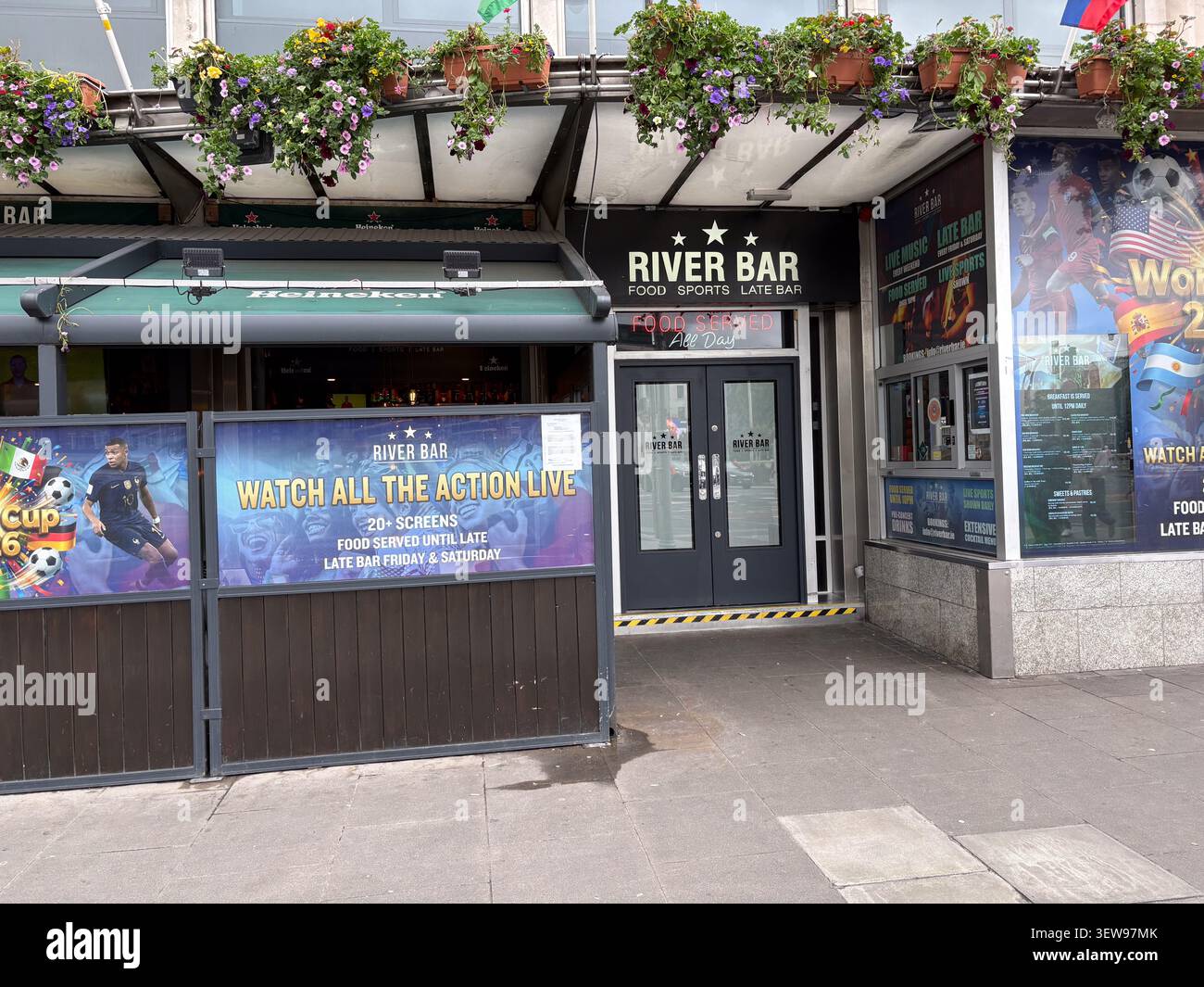 Vue extérieure du River Bar, un bar sportif de Dublin, en Irlande, avec des panneaux promotionnels pour les événements sportifs en direct et un coin salon extérieur. Banque D'Images