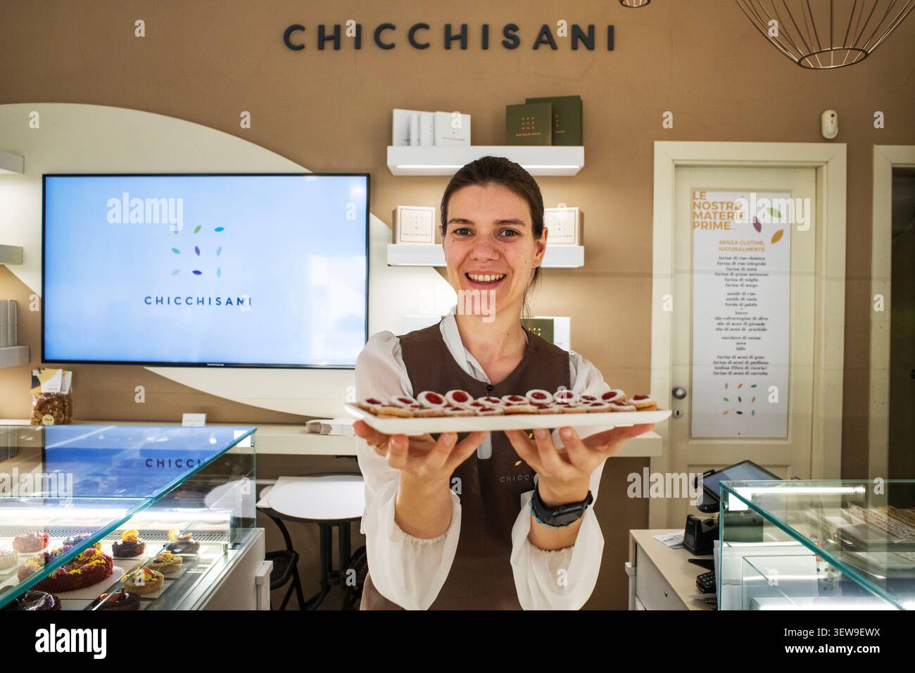 Un assistant de magasin souriant présentant un plateau de tartes à la confiture fraîchement cuites à l'intérieur de la pâtisserie Chicchisani à Turin, en Italie. Situé dans une ville renommée Banque D'Images