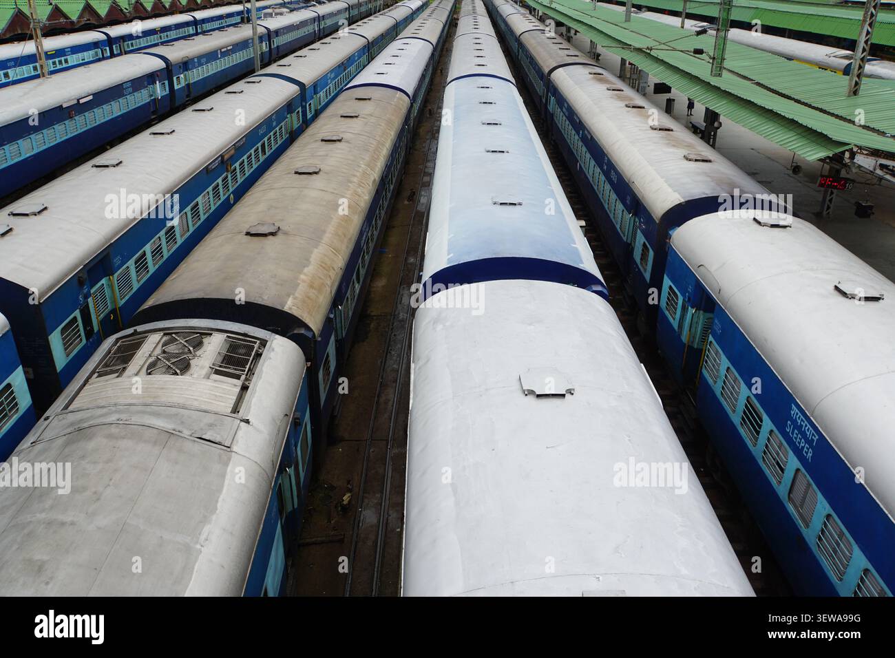 Une vue de dessus montre plusieurs longs trains de voyageurs bleus et blancs des chemins de fer indiens stationnés côte à côte sur les voies d'une gare ferroviaire. Les trains fe Banque D'Images