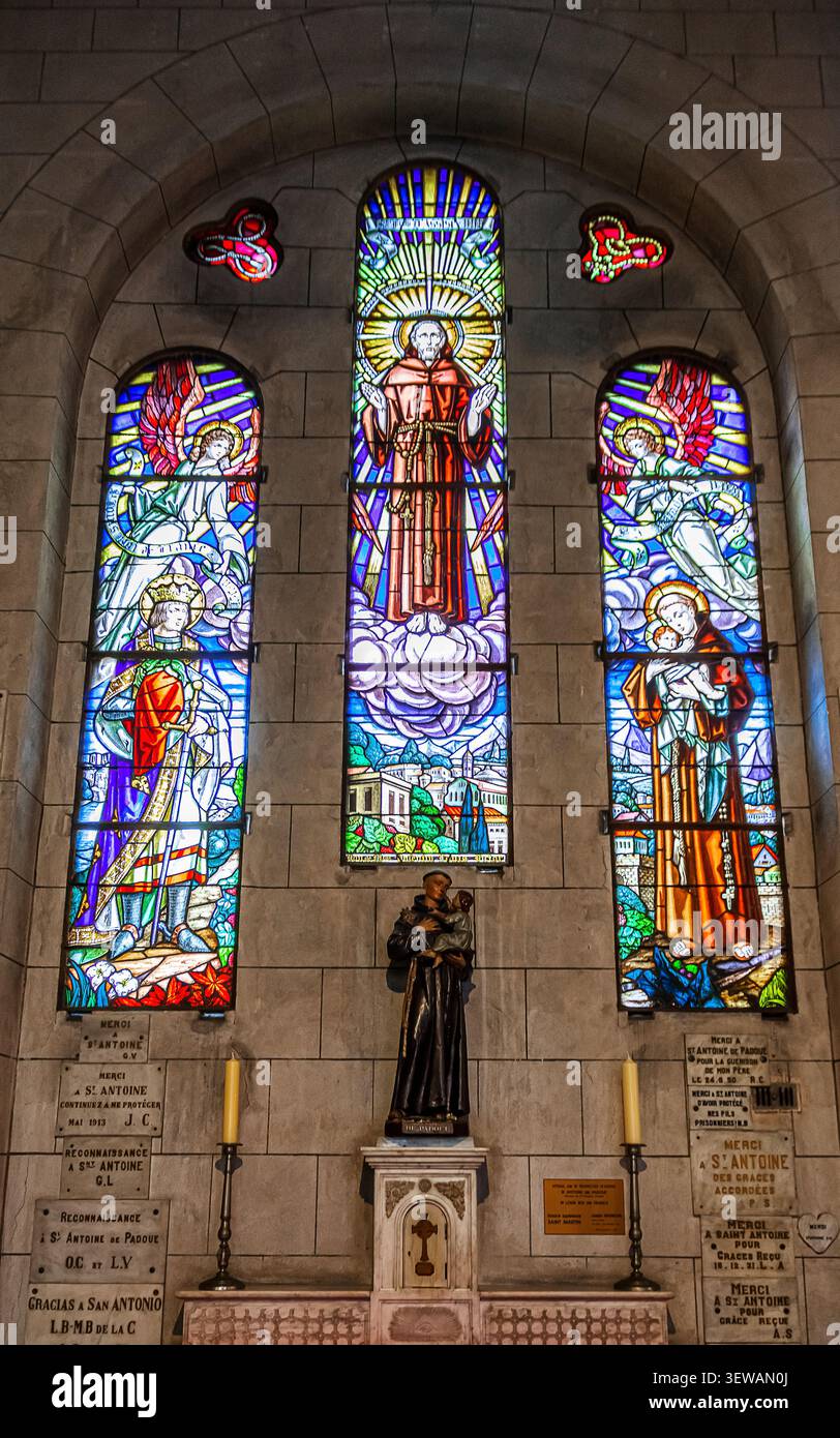 Statue de Saint Antoine de Padoue au pied d'une mosaïque de verre représentant des images sacrées dans la cathédrale de Monte-Carlo. Banque D'Images