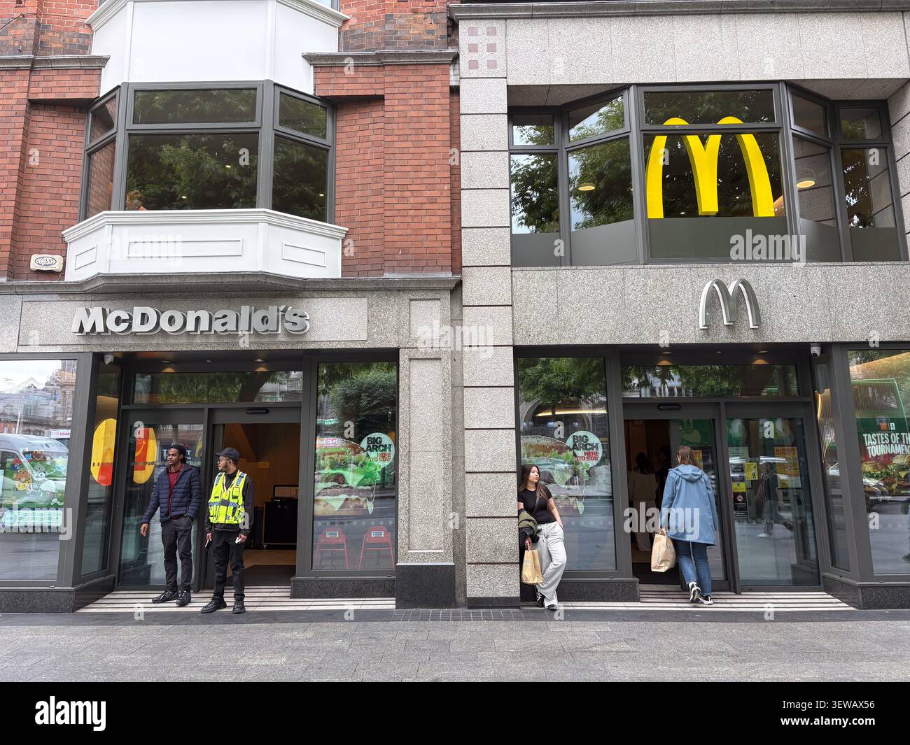 Extérieur d'un restaurant McDonald's à Dublin, Irlande, avec affichage moderne et vitrines avec clients et personnel de sécurité. Banque D'Images