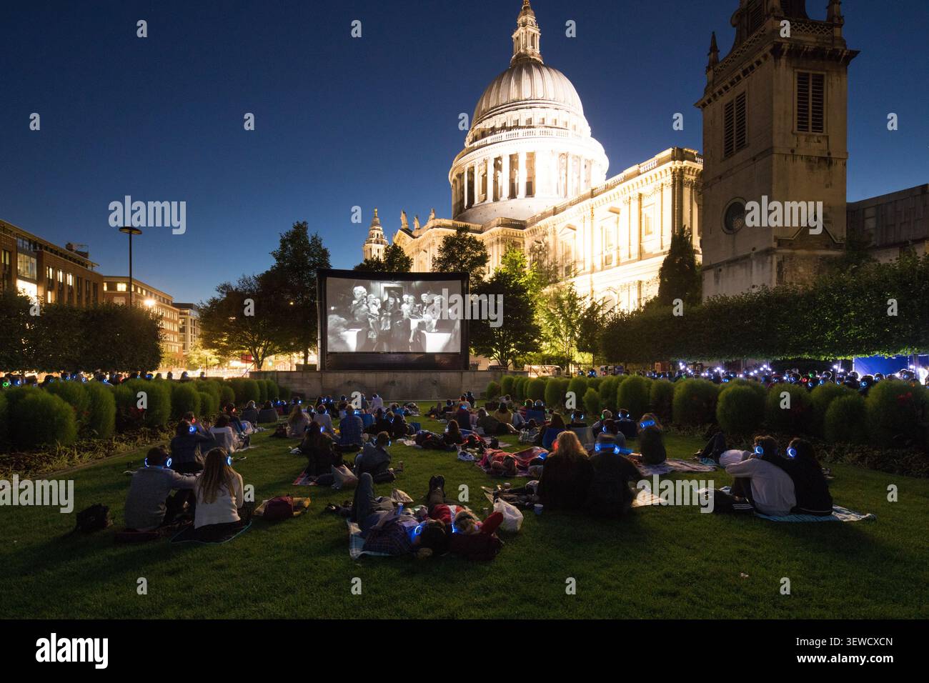 Les cinéphiles profitent d'un événement de cinéma en plein air silencieux à la cathédrale Paul de la City de Londres, en utilisant des écouteurs pour regarder un film. Banque D'Images