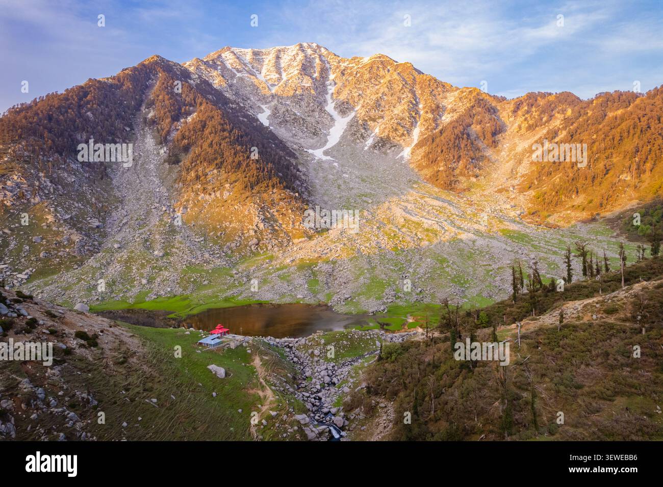 Vue aérienne du lac Kareri niché dans la chaîne de Dhauladhar, entouré de pentes rocheuses, de prairies verdoyantes et de sommets enneigés à Kareri, Himachal Prade Banque D'Images