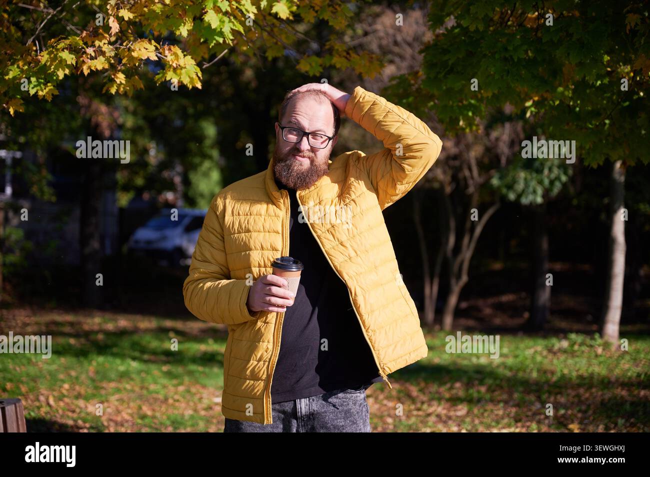 Homme avec café. Homme réfléchissant dans le parc. Homme occasionnel appréciant le matin d'automne. Figure masculine portant une veste jaune à la lumière du soleil. La personne avec une tasse jetable respire le calme pendant le matin paisible du parc Banque D'Images