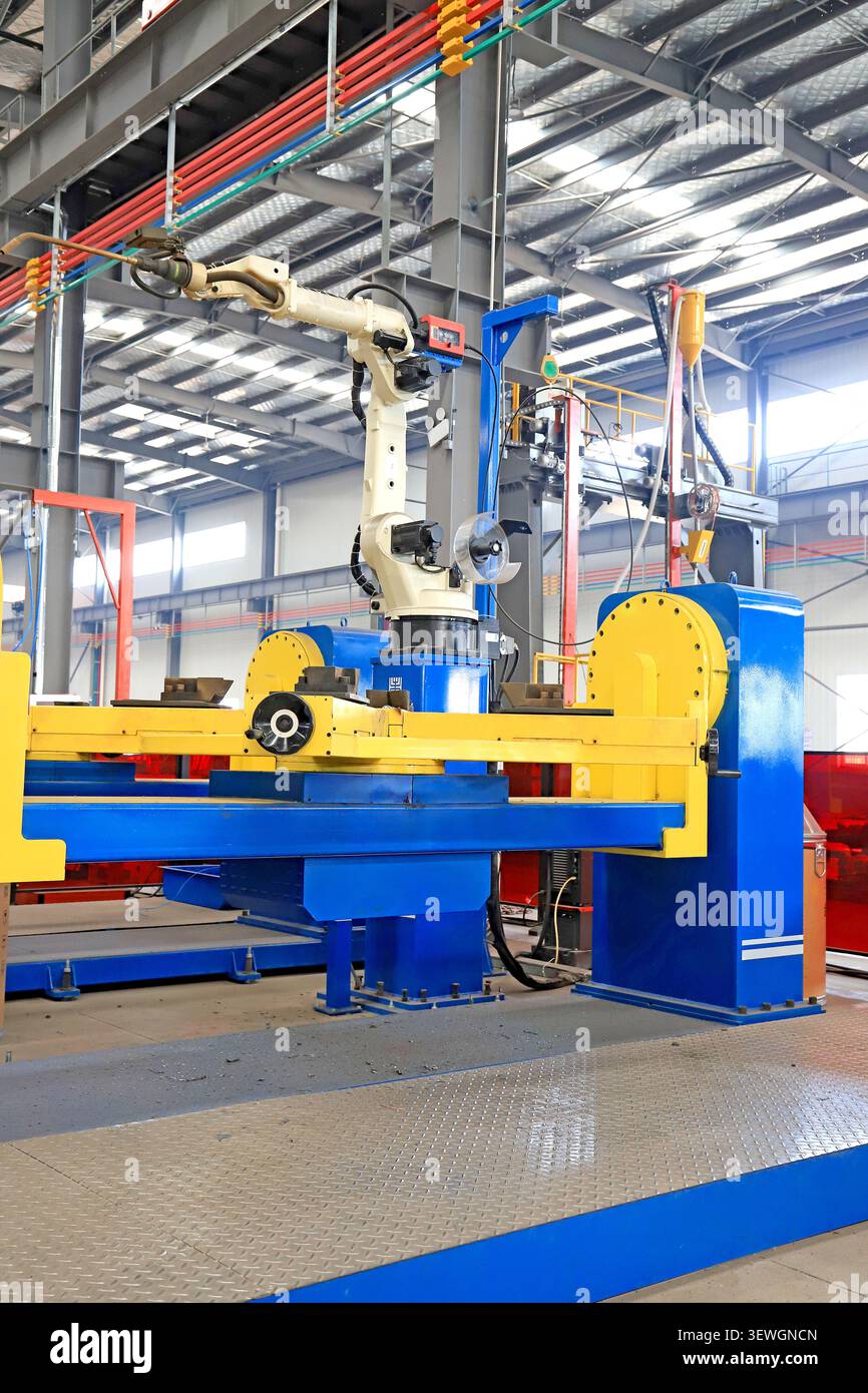 Prise de vue haute résolution et grand angle d'un bras de robot de soudage automatisé monté sur une machine robuste bleu et jaune éclatant dans un wor d'usine spacieux Banque D'Images