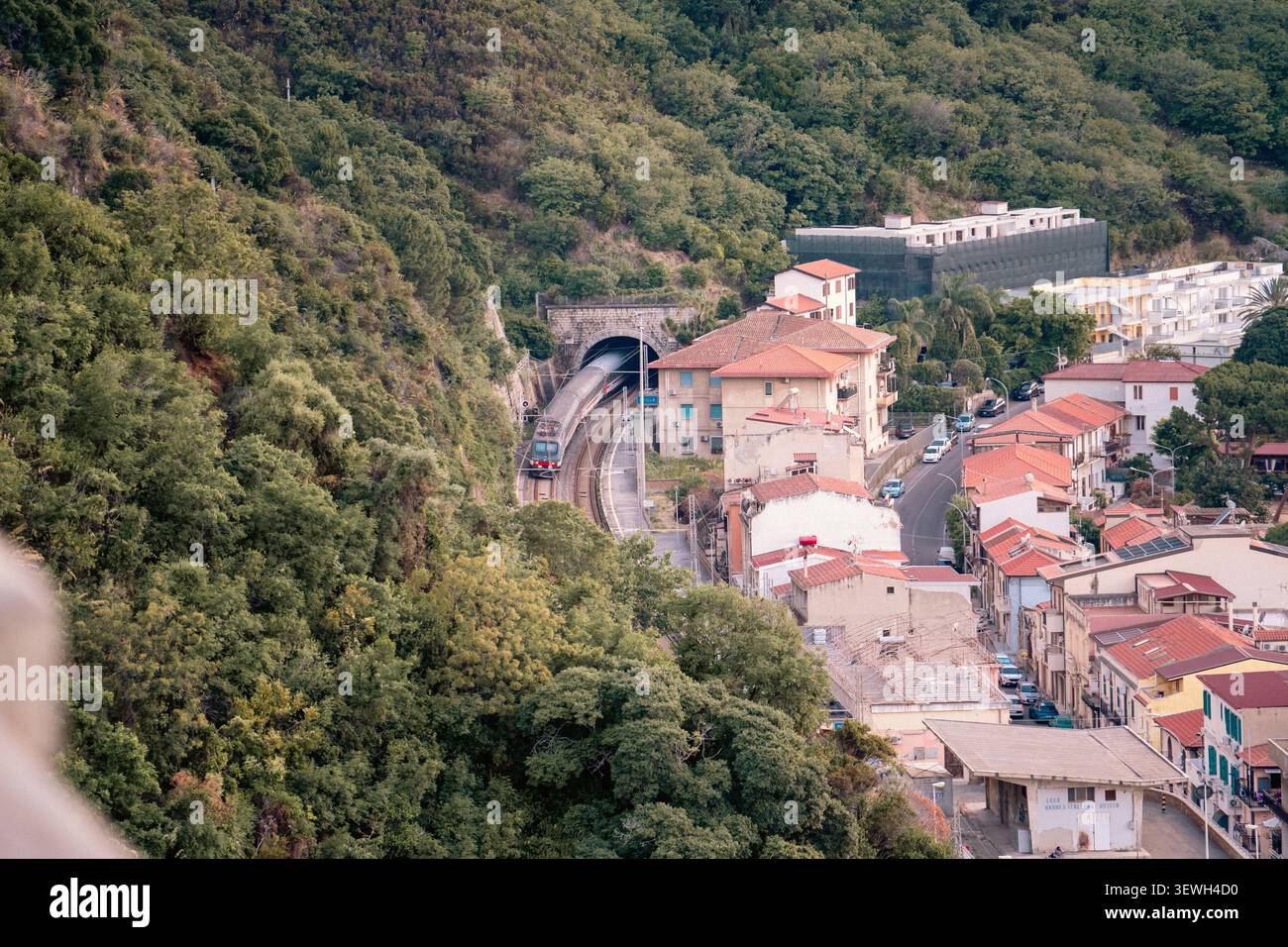 Vue en grand angle d'un train de voyageurs entrant dans un tunnel dans la ville de Scilla, Italie Banque D'Images
