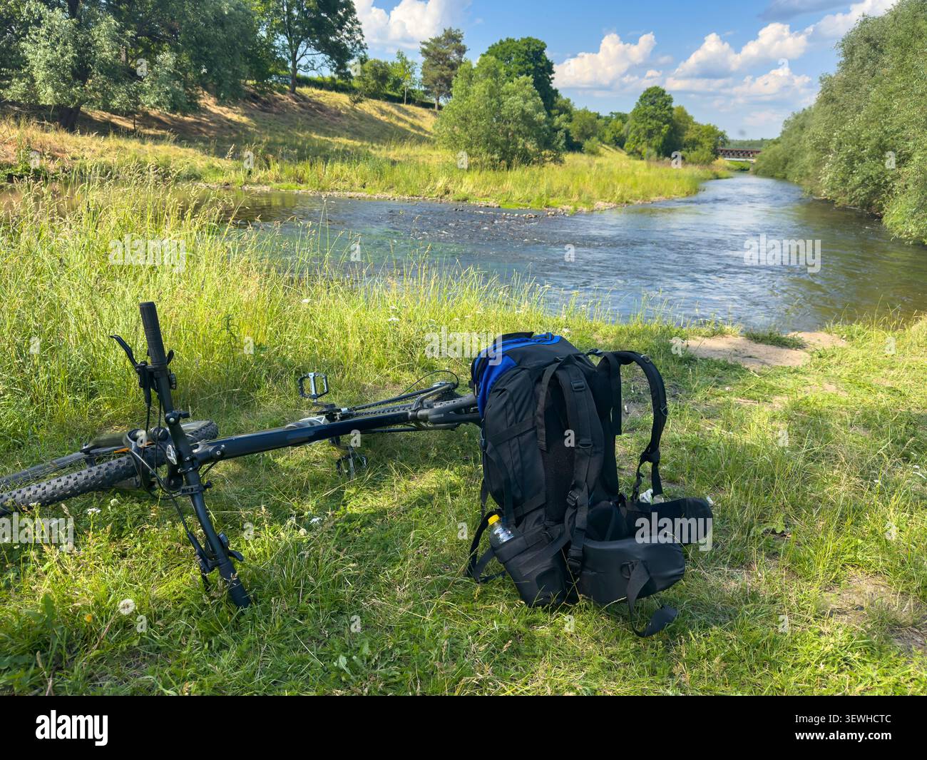 Dehors et à propos comme un routard avec un vélo et sac à dos par une rivière en été. Banque D'Images