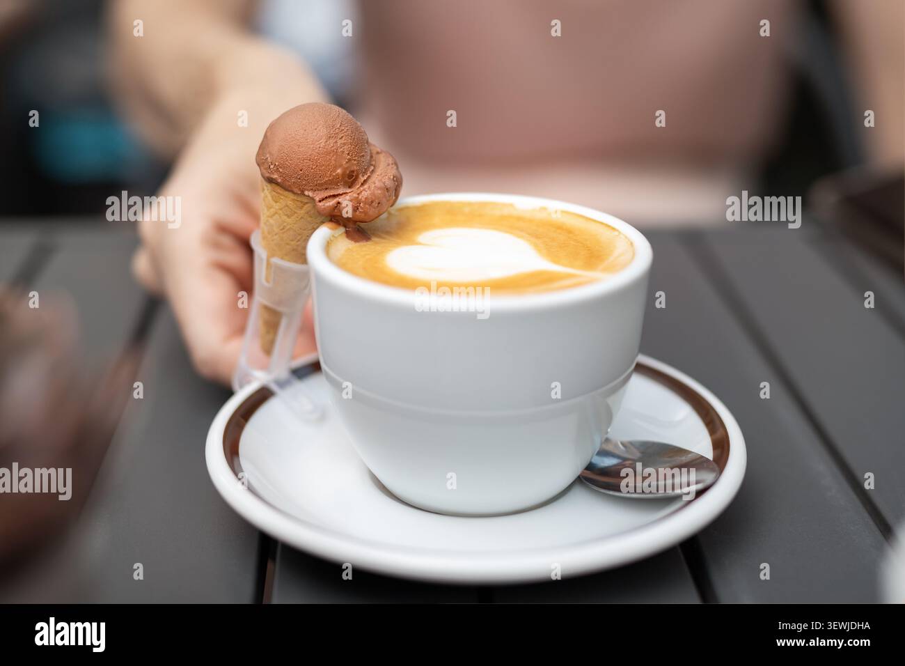 Un café au cœur de cappuccino crémeux latte art et un cornet de crème glacée au chocolat en miniature vous invitent. Pause café confortable mélange dessert, détente Banque D'Images