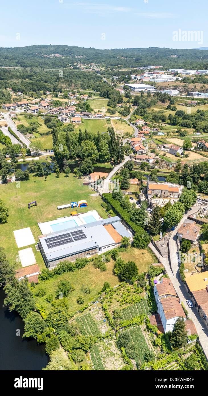 Zone de la ville d'Allariz avec des bâtiments, des panneaux solaires sur un complexe sportif, des piscines, une rivière, un paysage verdoyant et les infrastructures environnantes Banque D'Images