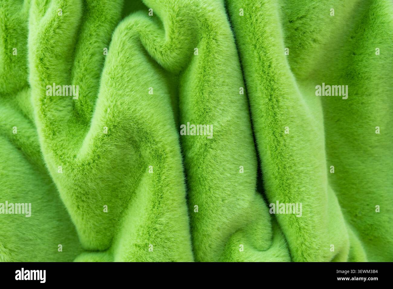 Gros plan de tissu vert éclatant en fausse fourrure, présentant une texture douce et des plis élégants Banque D'Images