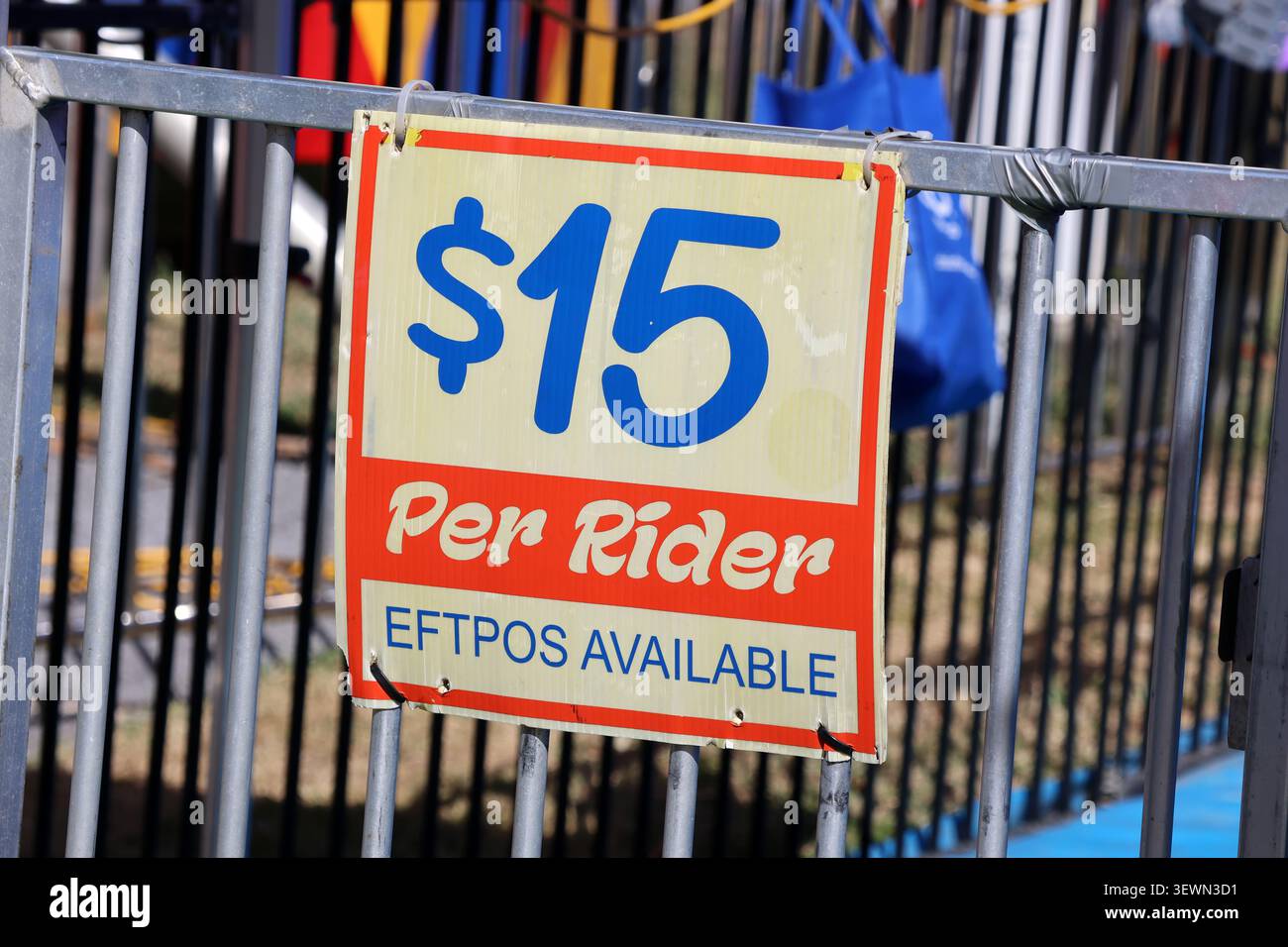 Un panneau de marché ou de foire lisant quinze dollars par cavalier avec EFTPOS texte disponible accroché sur une barrière métallique de contrôle des foules Banque D'Images