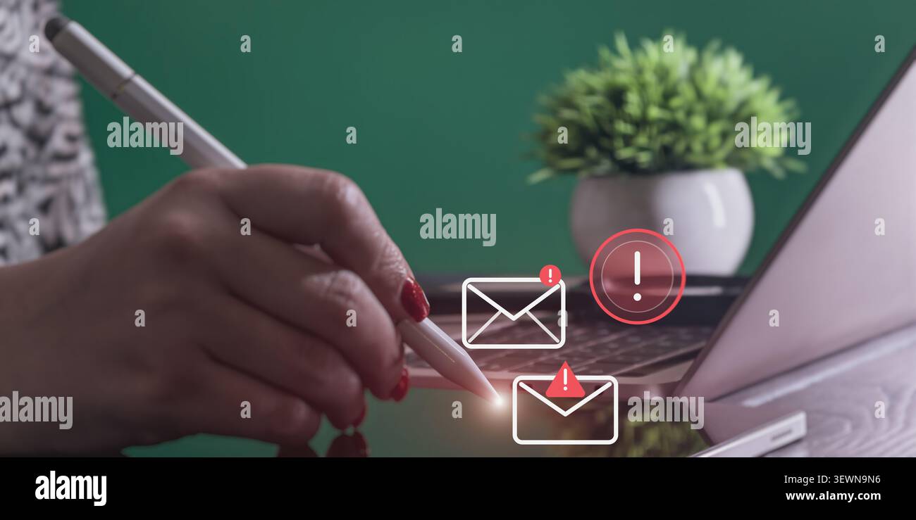 Gros plan de la main avec un stylet numérique touchant un écran avec des graphiques flottants de notification par e-mail urgent, ordinateur portable en arrière-plan. Banque D'Images