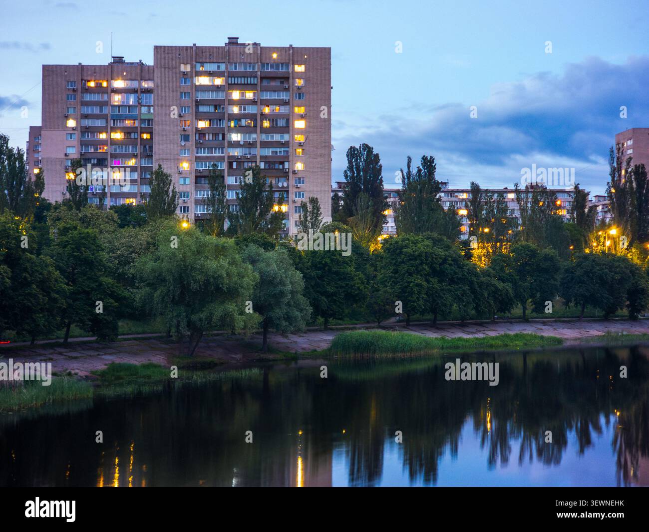 Bâtiments résidentiels urbains le long du canal Rusanivsky à Kiev réfléchissant sur l'eau tranquille au crépuscule, créant un sentiment d'habitation urbaine et ev Banque D'Images