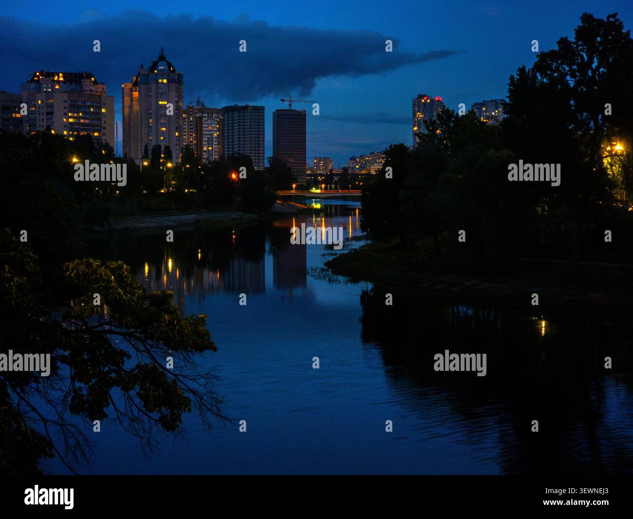 La ligne d'horizon de la zone résidentielle de Rusanivka se reflète dans le canal de la rivière Dnipro au crépuscule, mettant en valeur le développement urbain et les voies navigables tranquilles Banque D'Images