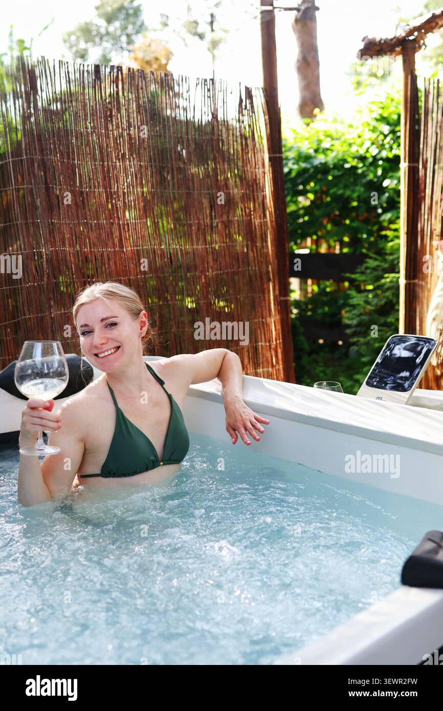 Expérience spa élégante avec une femme souriante dans un jacuzzi, profitant des loisirs, de l'auto-soin et de la détente. Banque D'Images