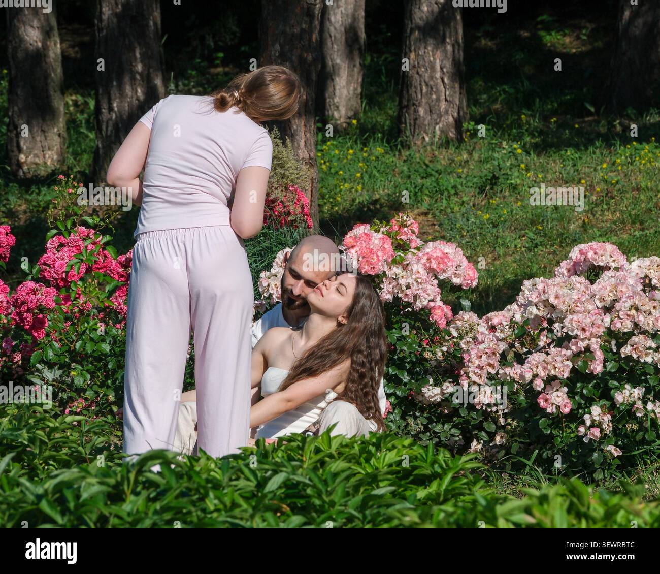 KIEV, UKRAINE - JUIN 2026 : un photographe réalise un couple lors d'une séance de photos de portrait en plein air entouré de fleurs en fleurs à Hryshko National Banque D'Images