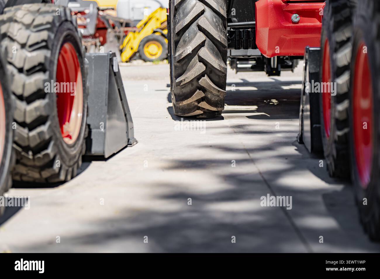 Vue au niveau du sol de pneus de véhicules de construction lourde avec des bandes de roulement en caoutchouc profondes stationnées sur une surface en béton conceptualisant la logistique et les machines Banque D'Images