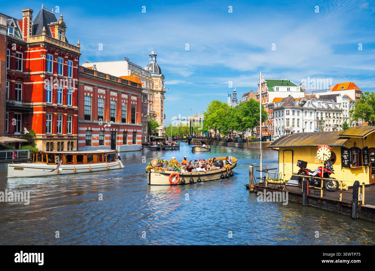 AMSTERDAM, PAYS-BAS – 21 mai 2026 : des touristes se promènent le long des canaux historiques d'Amsterdam, entourés d'architecture néerlandaise traditionnelle par une journée ensoleillée. Banque D'Images