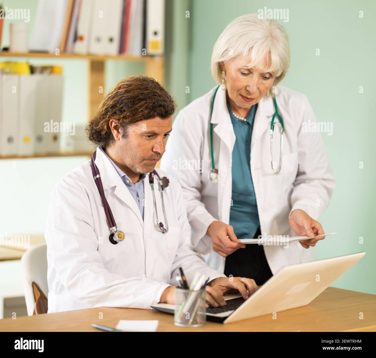 Femme âgée et médecins adultes travaillant sur ordinateur portable dans le cabinet médical Banque D'Images