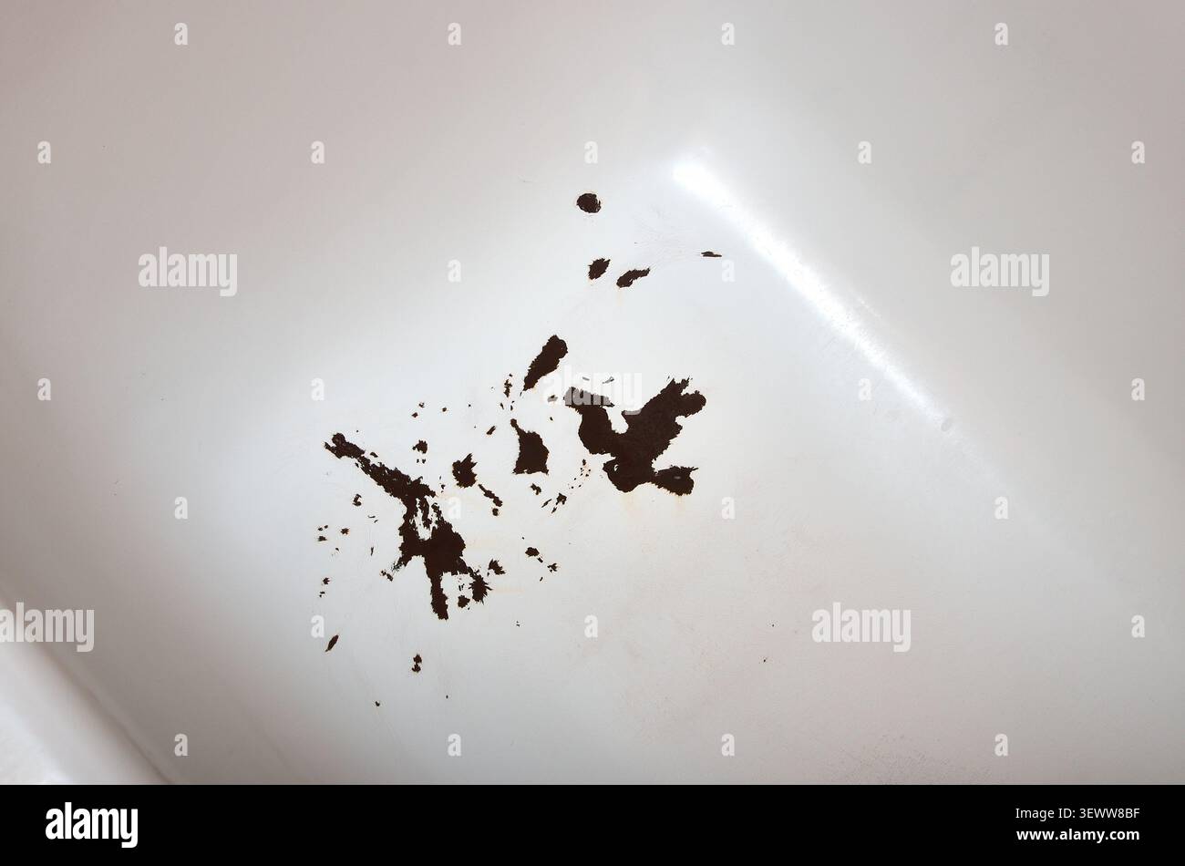 Vue rapprochée d'une baignoire blanche endommagée présentant de l'émail fissuré, de la corrosion du métal et des taches de rouille foncée Banque D'Images