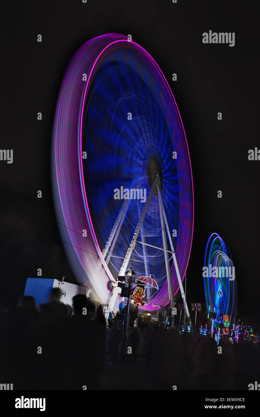 Grandes roues avec flou de mouvement et lumières colorées au Navipark 2024, à Móstoles, Madrid, Espagne. Banque D'Images