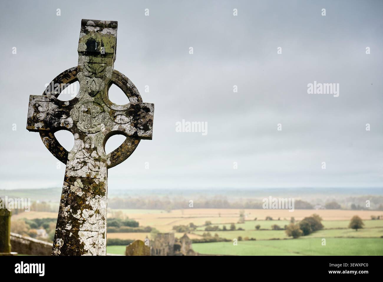 Croix celtique érodée surplombant la campagne au Rocher de Cashel, Irlande Banque D'Images